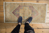 Distressed vintage Oushak mat runner, showing faded violet, beige, turquoise patterns underfoot.