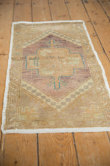 Oushak rug corner displaying intact side selvage, worn pile, and violet, beige, turquoise scalloped medallion.