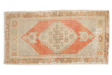 Distressed vintage Oushak rug with faded brick red medallion, geometric floral patterns, and worn beige field.