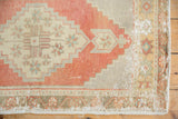 Distressed vintage Oushak rug corner, faded geometric floral border, visible foundation.