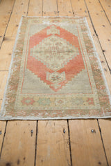 Distressed texture on vintage Oushak rug corner, featuring faded brick red and light beige.