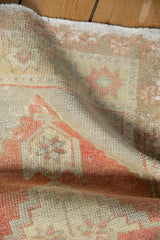 Distressed Oushak rug, soft worn pile, faded blush, beige, and seafoam green geometric motifs.