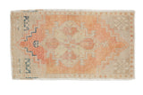 Distressed vintage Oushak rug mat with faded apricot, blush, beige, and navy stepped geometric design.