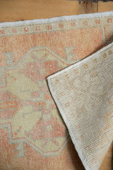 Oushak rug's distressed apricot and beige pile with visible hand-knotted foundation.