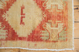 Vintage distressed Oushak rug corner, showing worn knot heads, red and beige geometric pattern.