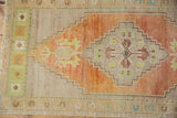 Distressed vintage Oushak rug corner, showing even wear and abrashed orange pile.