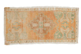 Distressed vintage Oushak rug mat featuring a pale orange, seafoam green, and ivory diamond medallion.