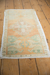 Distressed Oushak rug mat's low pile, pale rust, seafoam green motifs, and intact side selvage.