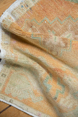 Folded detail of the distressed pile and muted colors on a vintage Oushak rug.
