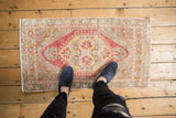 Distressed Oushak rug with hexagonal medallion, floral palmettes, brick red, beige, and pale turquoise.