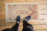 Distressed vintage Oushak mat: central medallion, grape motif, soft burgundy, saffron, tangerine.