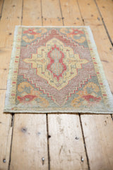 Distressed vintage Oushak rug mat showing a geometric medallion and soft, warm tones.