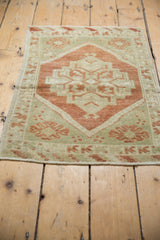 Distressed Oushak rug border showing sea foam green, copper motifs, and worn pile texture.