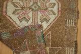 Distressed vintage Oushak rug folded, showing coffee brown pile, ivory-pink pattern, and hand-knotted underside.