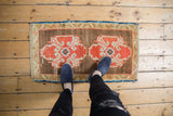 Distressed texture on vintage Oushak rug featuring orange rust ram's horn motifs.