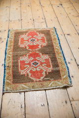 Distressed Oushak rug detail: bright orange-rust ram's horn motif, navy blue side.