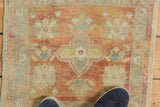 Distressed vintage Oushak rug detail, featuring faded raspberry and seafoam floral motifs and low pile.