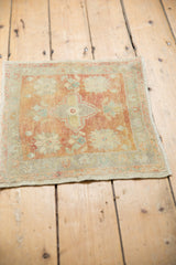 Distressed Oushak rug corner, showing faded floral vinery, dusty red, and beige tones.
