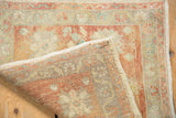 Distressed vintage Oushak rug corner showing hand-knotted reverse and pile with muted raspberry, beige, and green florals.