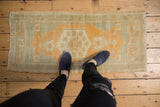 Distressed vintage Oushak rug with faded gold, beige, ivory, and silver tones; even wear.