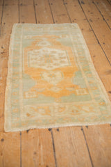 Distressed Oushak rug pile with muted gold and soft green geometric floral motifs.