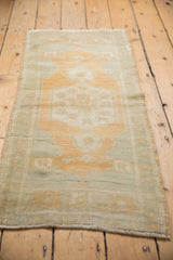 Distressed Oushak rug runner close-up, showing worn sage and faded gold geometric patterns.