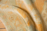 Distressed Oushak rug close-up: worn pile, exposed knot heads, soft gold beige tones.