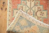 Distressed Oushak rug with worn pile texture, original selvage, and woven back in muted tones.