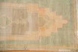 Distressed Oushak rug pile shows apricot, beige, green stepped motifs and secured fringe.