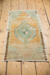 Distressed Oushak rug's thin banded brown border and faded teal geometric abrash.