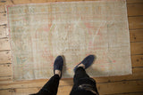 Distressed Oushak rug with soft blush and ivory, showing worn pile and faded medallion pattern.