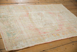 Distressed pile texture with faded ivory, blush, and seafoam green, foundation visible.