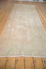 Distressed field of vintage Oushak runner with faint blush and powder blue floral motifs.
