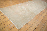 Distressed Oushak runner side, with pale blush floral border and abrashed field showing even wear.