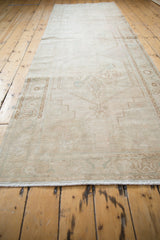 Distressed Oushak rug runner side with beige pile, visible wear, and intact selvage.