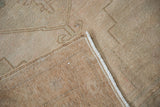 Folded vintage distressed Oushak rug, revealing its soft worn pile, hand knotted backing, and intact side cord.