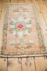 Distressed Oushak rug with fuchsia and turquoise floral motifs, beige field, coffee brown vine border.