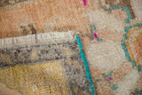 Distressed Oushak rug's beige pile, turquoise edge, short fringe, and subtle fuchsia.