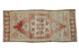 Vintage distressed Oushak rug with scalloped floral medallion in pale red, silver, and seafoam.