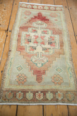 Distressed Oushak runner featuring a faded wine red medallion on a seafoam green field.