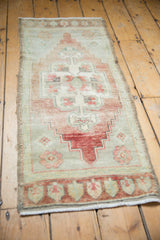 Worn pile and faded colors of distressed Oushak runner's scalloped floral medallion.