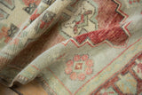 Distressed vintage Oushak pile texture showing red floral motifs and even wear.