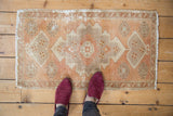 Distressed Oushak rug pile with mostly even wear, foundation showing, apricot and beige.