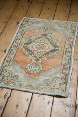 Distressed Oushak rug with dusty rust field, floral medallion, and slate meandering vine border.