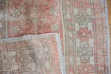 Distressed Oushak rug pile showing dusty blush, seafoam colors, and original selvage with woven foundation.