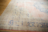 Distressed vintage Oushak carpet with faded pale rose, ivory, and blue floral motifs.
