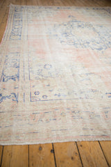 Distressed vintage Turkish Oushak rug with pale dusty rose, ivory field, and faded blue motifs.