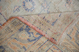 Vintage distressed Oushak rug folded, revealing worn pile, woven foundation, and pink selvage.