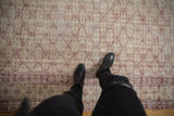 Distressed vintage Oushak rug with faded red trellis pattern on ivory, foundation showing.