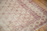 Distressed Oushak rug with foundation showing, revealing muted red trellis and starburst border.